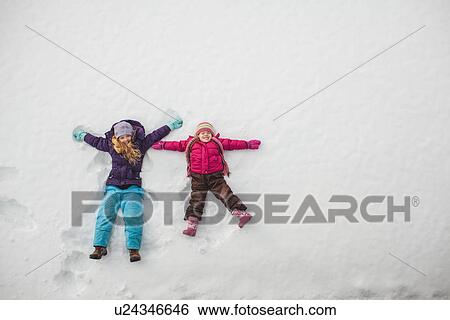 Two sisters playing, making snow angels in snow View Large Photo Image Stock Photograph - Two sisters playing, making snow angels in snow. Fotosearch