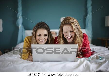 Two teenage girls looking at laptop in bedroom View Large Photo Image Picture - Two teenage girls looking at laptop in bedroom. Fotosearch