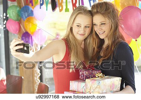 Stock Photo - Two teenage girls taking selfie at birthday party. Fotosearch