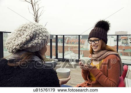Two young adult women having coffee on rooftop terrace View Large Photo Image Stock Photo - Two young adult women having coffee on rooftop terrace. Fotosearch