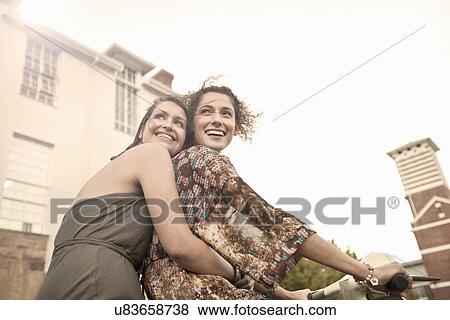 Stock Photo - Two young women riding moped. Fotosearch