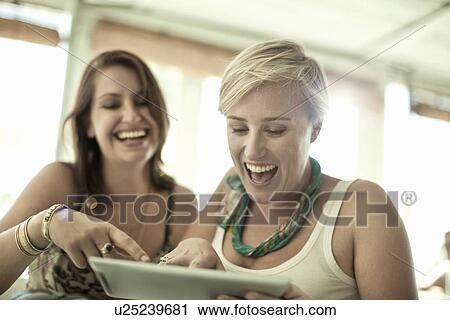 Two young women using digital tablet in cafe bar View Large Photo Image Stock Image - Two young women using digital tablet in cafe bar. Fotosearch