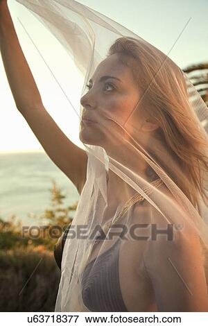 Stock Photo - Woman in bikini holding up sheer scarf. Fotosearch