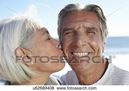 Stock Photo - Woman pecking man on cheek. Fotosearch