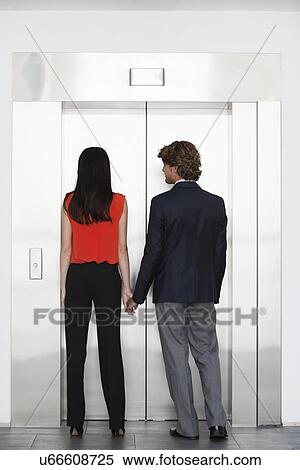 Stock Photography - Work colleagues holding hands in front of elevator. Fotosearch