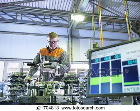 Stock Image - Worker assembling and testing clutches on rig in factory. Fotosearch