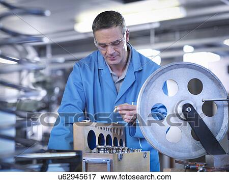 Stock Photo - Worker calibrating equipment for automotive use. Fotosearch