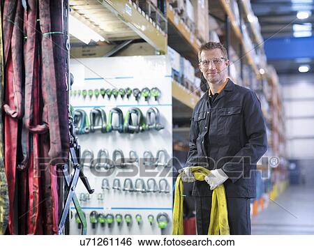 Stock Photograph - Worker in engineering factory holding lifting gear, portrait. Fotosearch