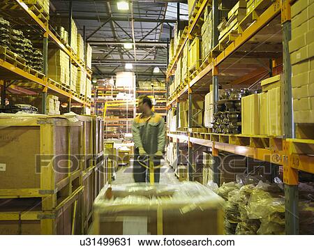 Stock Image - Worker in storage area of factory. Fotosearch