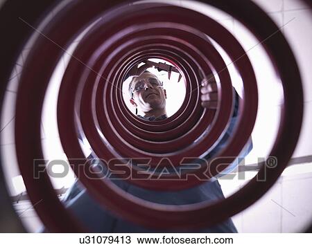 Stock Image - Worker inspecting spring in laboratory, low angle view. Fotosearch