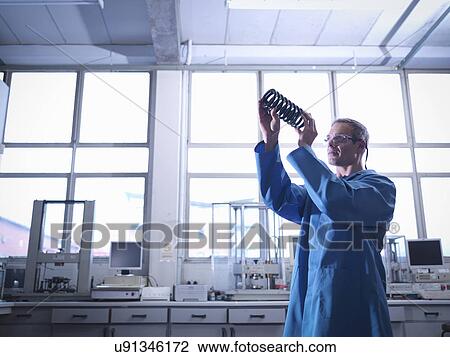 Stock Image - Worker inspecting spring in laboratory. Fotosearch