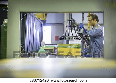 Stock Image -  Worker on packing line in factory. Fotosearch