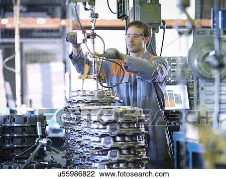 Stock Image - Worker on production line in industrial clutch factory. Fotosearch
