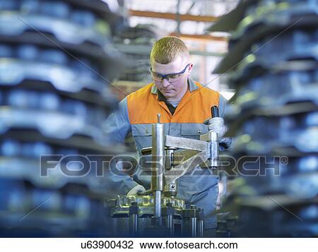 Stock Image - Worker on production line in industrial clutch factory. Fotosearch