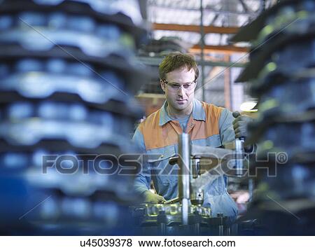 Stock Photo - Worker on production line in industrial clutch factory. Fotosearch