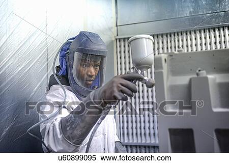 Stock Photography - Worker paint spraying industrial gearboxes in factory. Fotosearch