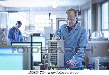 Picture - Worker testing equipment on production line. Fotosearch