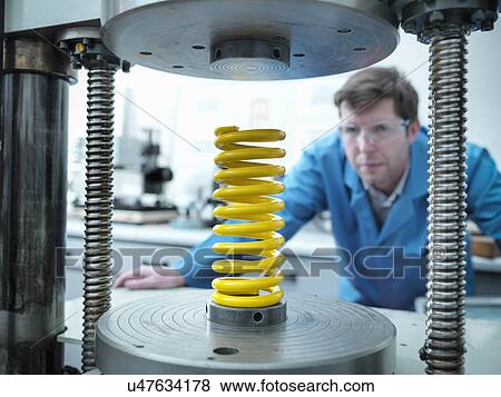 Stock Photo - Worker testing spring for durability in laboratory. Fotosearch