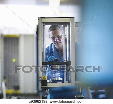 Stock Photo - Worker using equipment to test spring. Fotosearch