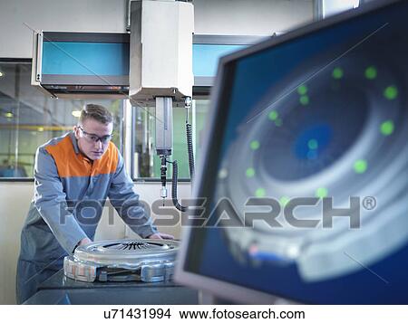Picture -  Worker using measuring device in factory. Fotosearch