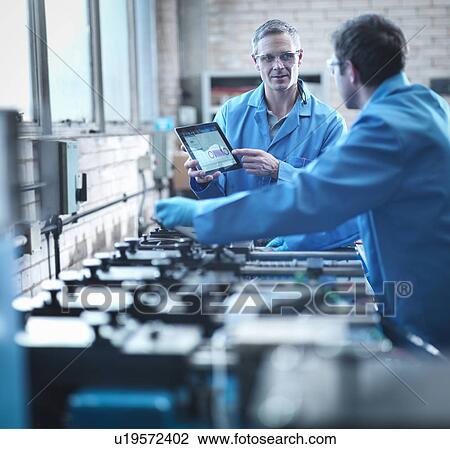 Stock Image - Workers using digital tablet for testing springs in laboratory. Fotosearch