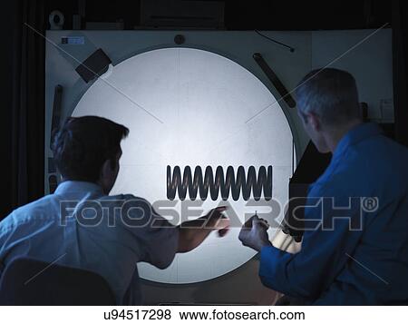 Stock Photo - Workers using shadow graph machine to inspect spring. Fotosearch