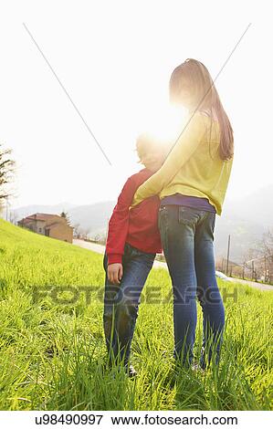 Young boy and older sister in grassy field View Large Photo Image Stock Photo - Young boy and older sister in grassy field. Fotosearch