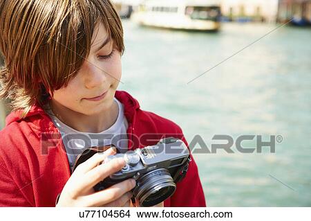 Picture - Young boy checking photographs on camera, Venice, Italy. Fotosearch