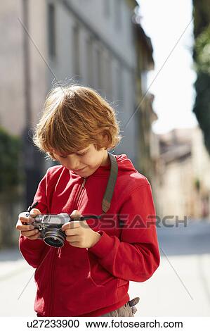 Stock Image - Young boy checking photographs on street, Province of Venice, Italy. Fotosearch