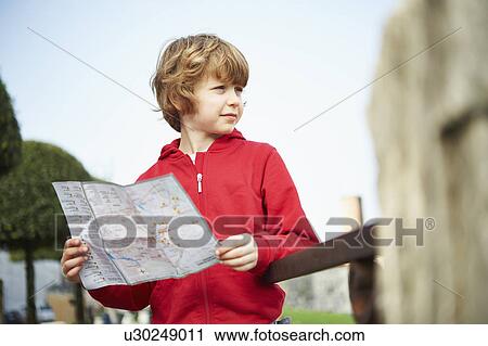 Stock Image - Young boy holding map in park, Province of Venice, Italy. Fotosearch