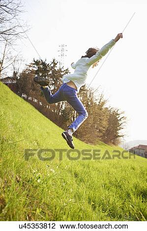 Young boy jumping down steep grassy field View Large Photo Image Stock Image - Young boy jumping down steep grassy field. Fotosearch
