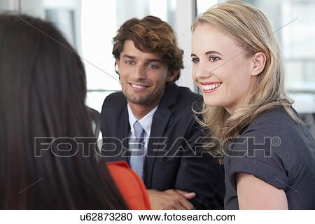 Stock Image - Young business colleagues having team meeting in office. Fotosearch