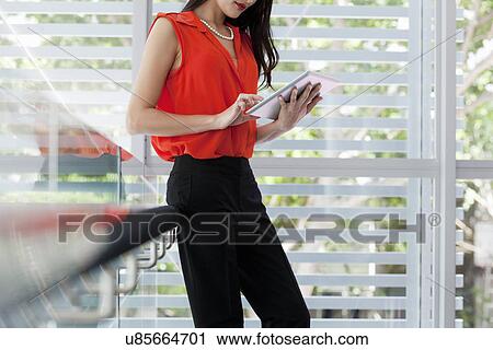 Stock Image - Young businesswoman using digital tablet on balcony. Fotosearch