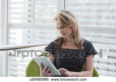Stock Photography - Young businesswoman using digital tablet in office. Fotosearch