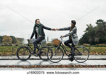 Stock Photography - Young couple cycling on street. Fotosearch