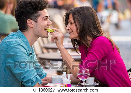 Young couple eating macaroon at pavement cafe, Paris, France View Large Photo Image Stock Photo - Young couple eating macaroon at pavement cafe, Paris, France. Fotosearch
