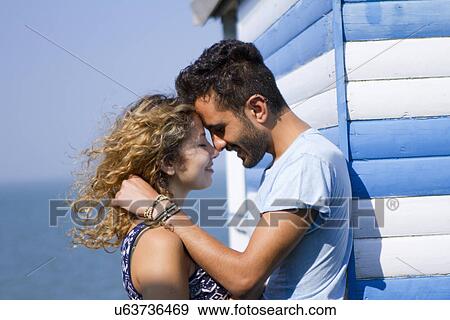 Stock Photo - Young couple hugging by beach hut. Fotosearch
