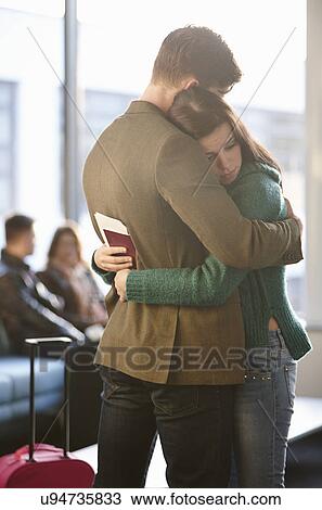 Young couple hugging in airport View Large Photo Image Stock Image - Young couple hugging in airport. Fotosearch