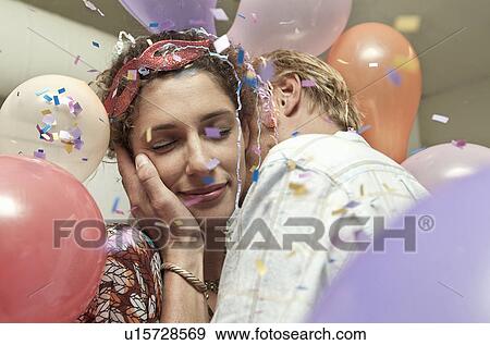 Stock Photo - Young couple kissing at party. Fotosearch