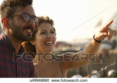 Young couple laughing, woman pointing View Large Photo Image Stock Image - Young couple laughing, woman pointing. Fotosearch