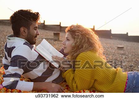 Young couple lying on beach, woman reading book View Large Photo Image Stock Image - Young couple lying on beach, woman reading book. Fotosearch