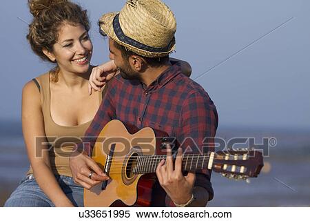 Stock Photography - Young couple, man playing guitar. Fotosearch