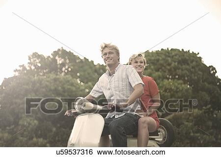 Stock Photograph - Young couple riding moped. Fotosearch