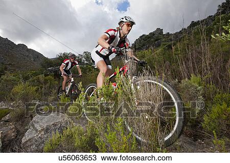Young couple riding mountain bikes down mountain View Large Photo Image Stock Image - Young couple riding mountain bikes down mountain. Fotosearch