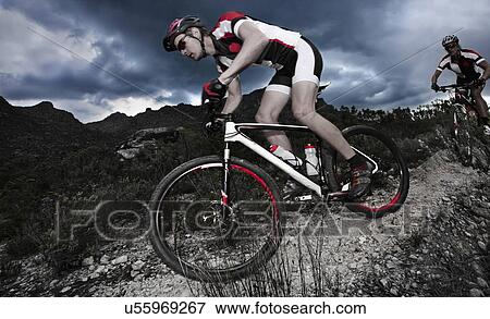 Young couple riding mountain bikes down mountain path View Large Photo Image Stock Photo - Young couple riding mountain bikes down mountain path. Fotosearch