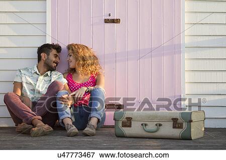 Young couple sitting by beach hut with suitcase View Large Photo Image Stock Photo - Young couple sitting by beach hut with suitcase. Fotosearch