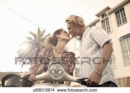 Picture - Young couple with moped kissing. Fotosearch