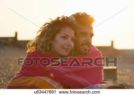 Young couple wrapped in towel on beach View Large Photo Image Stock Image - Young couple wrapped in towel on beach. Fotosearch