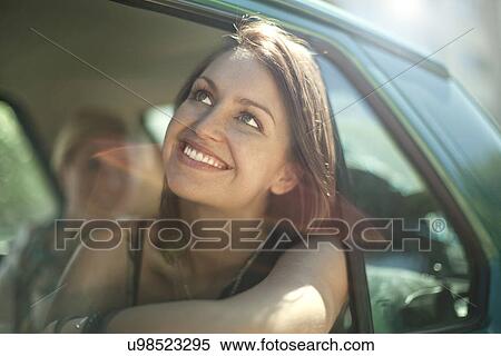 Stock Photography - Young female leaning out of car window. Fotosearch