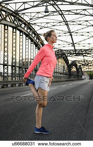Young female runner stretching on bridge View Large Photo Image Stock Image - Young female runner stretching on bridge. Fotosearch